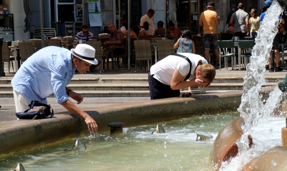 Un grupo de turistas moja sus cabezas con agua de una fuente pública en Valencia. REUTERS/Heino Kalis