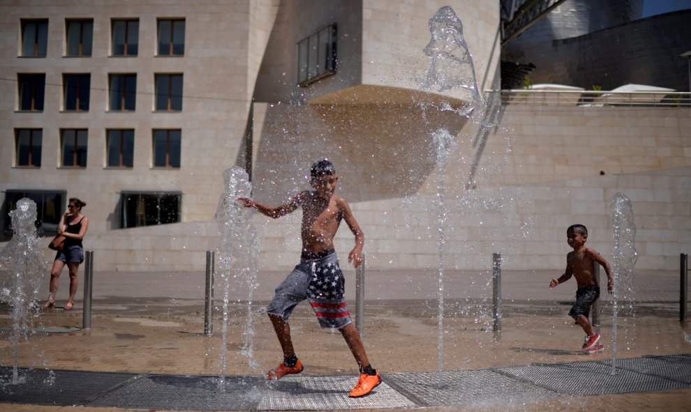 Varios niños juegan con el agua de una fuente cercana al museo Guggenheim en Bilbao. REUTERS/Vicent West