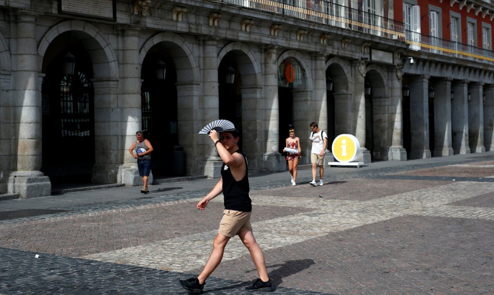 Un hombre sujeta un abanico sobre su cabeza para intentar protegerse de los fuertes rayos del sol en Madrid. REUTERS/Javier Barbancho
