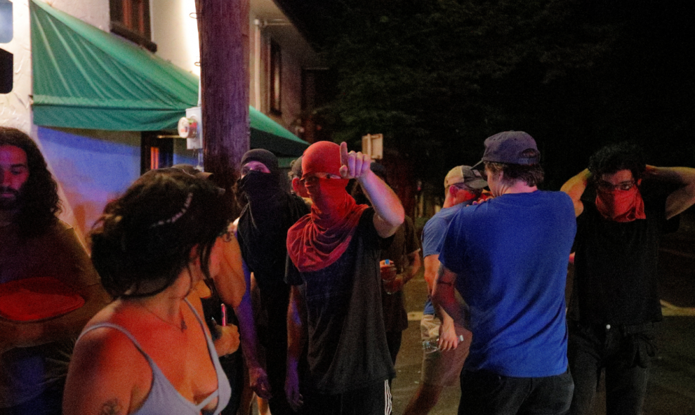 Uno de los manifestantes con el rostro cubierto señala hacia algún lugar | REUTERS