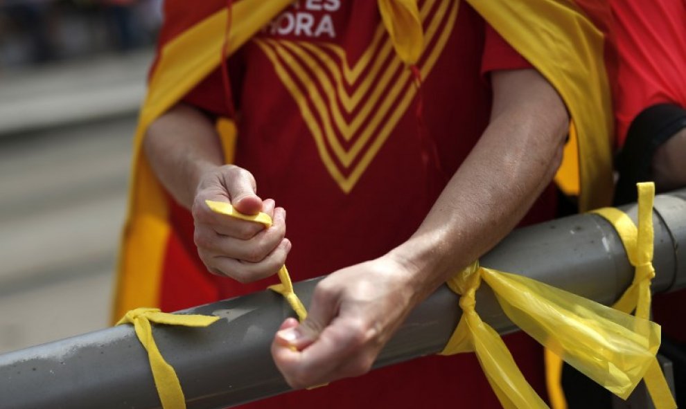 Un manifestante ata lazos amarillos. Los organizadores de la manifestación explicaron que tienen unos 460.000 inscritos. / AFP - PAU BARRENA