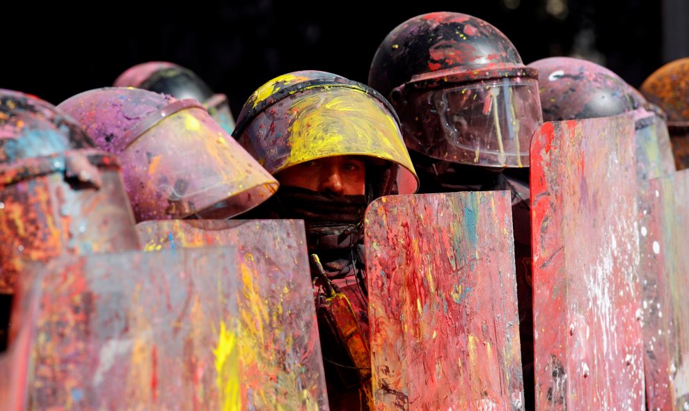 Los Mossos d'Esquadra se parapetan bajo sus escudos manchados por la pintura lanzada por los manifestantes./REUTERS