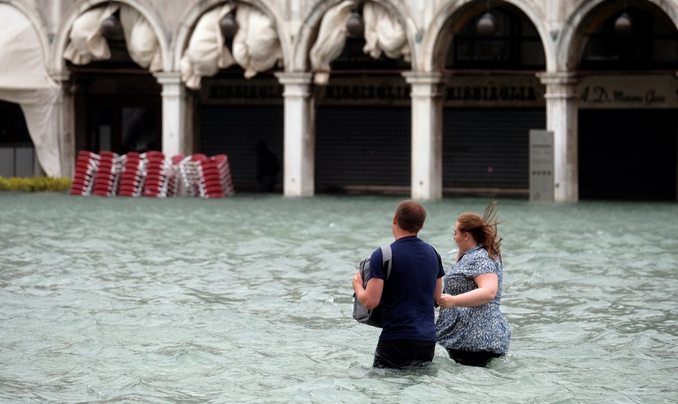 Una pareja intenta hacerse hueco en la inundada plaza de San Marcos. REUTERS/Manuel Silvestri