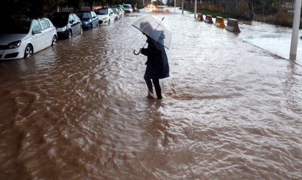 Una persona cruza una calle inundada durante la tarde del viernes en la que el temporal de lluvia torrencial ha azotado por tercera jornada consecutiva la provincia de Valencia. EFE/Kai Försterling