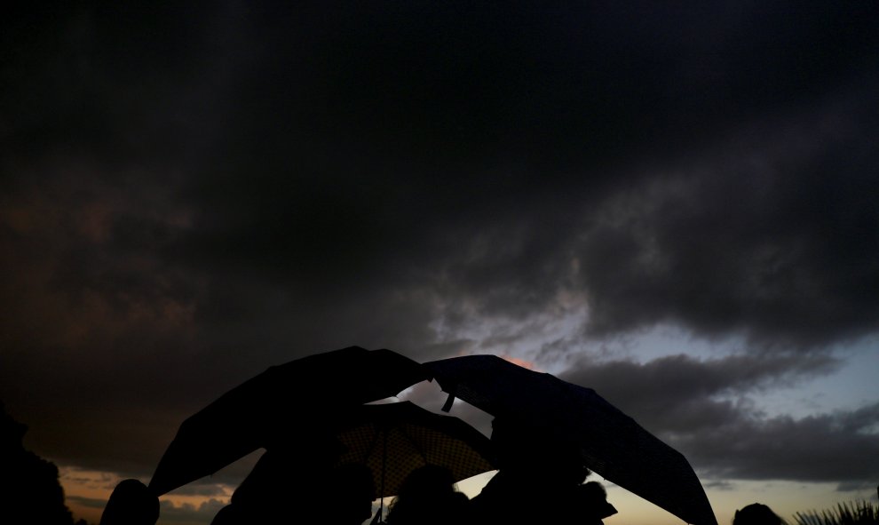 Un grupo de personas se refugia de la lluvia con sus paraguas en el parque madrileño del Templo de Debod. REUTERS/Sergio Perez