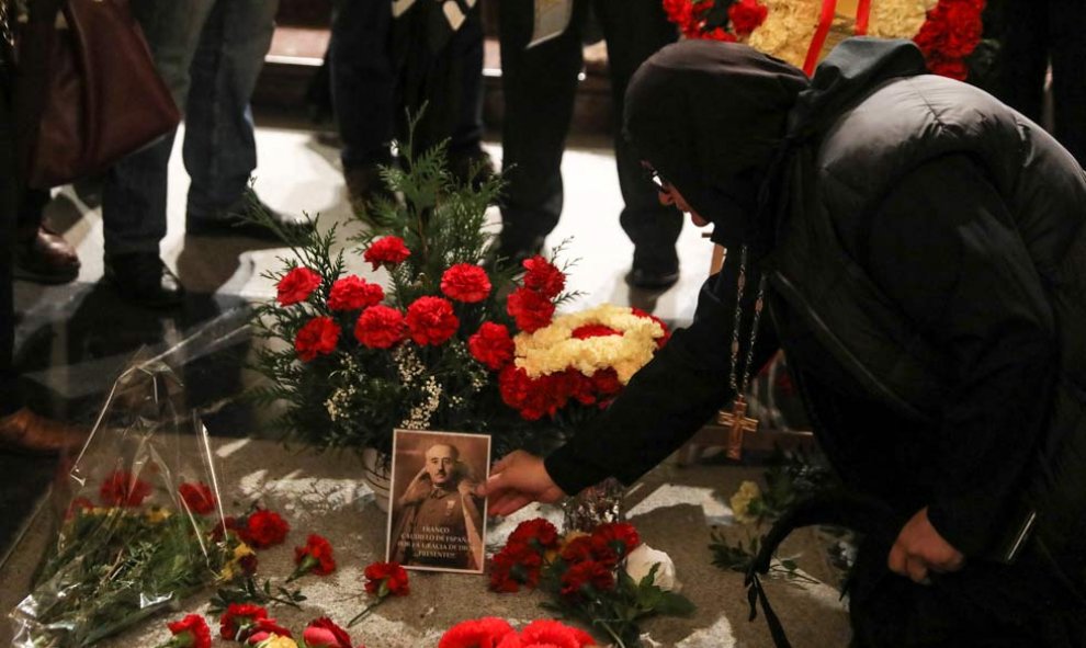 Una mujer coloca una imagen de Franco sobre su tumba. (SUSANA VERA | REUTERS)