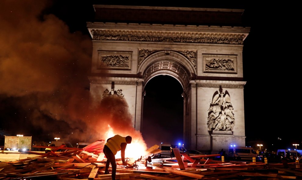 Un manifestantes de los llamados "chalecos amarillos" prende fuego a una barrica frente al Arco del Triunfo de París en la manifestación contra el alza de precio de los carburantes.- REUTERS/Benoit Tessier
