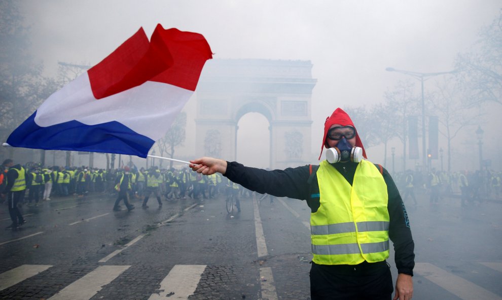 Un hombre sujeta una bandera de Francia. De fondo, el Arco del Triunfo. Stephane Mahe./REUTERS