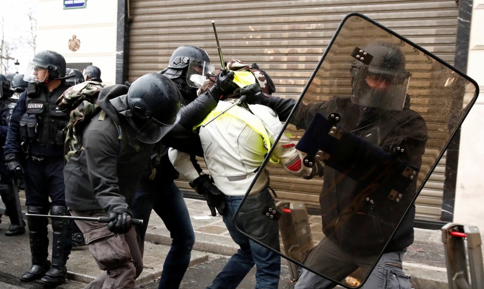 Los antidisturbios, protegidos con escudos, detienen a un manifestante de los chalecos amarillos en París. REUTERS/Christian Hartmann