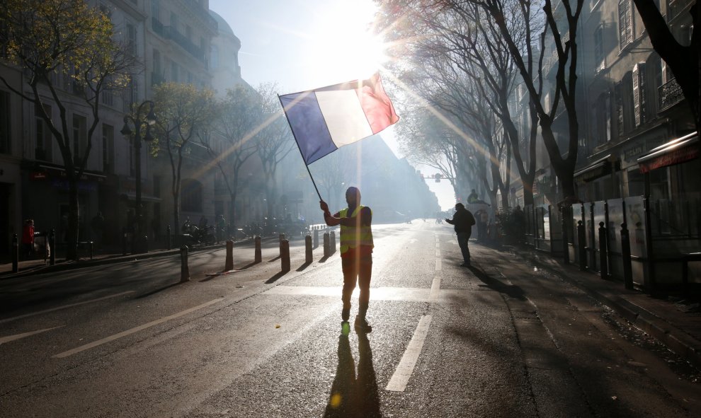 Uno de los manifestantes de los chalecos amarillos porta una bandera de Francia en las calles de Marsella.- REUTERS/Jean-Paul Pelissier