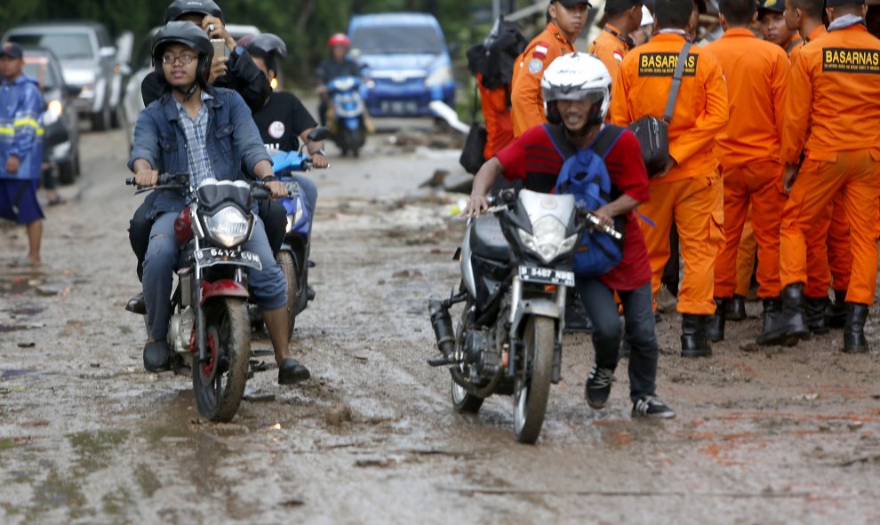 Residentes locales con sus scooters en una carretera embarrada después de un tsunami en el Estrecho de Sunda en Pandeglang, Banten, Indonesia.- EFE/EPA/ADI WEDA