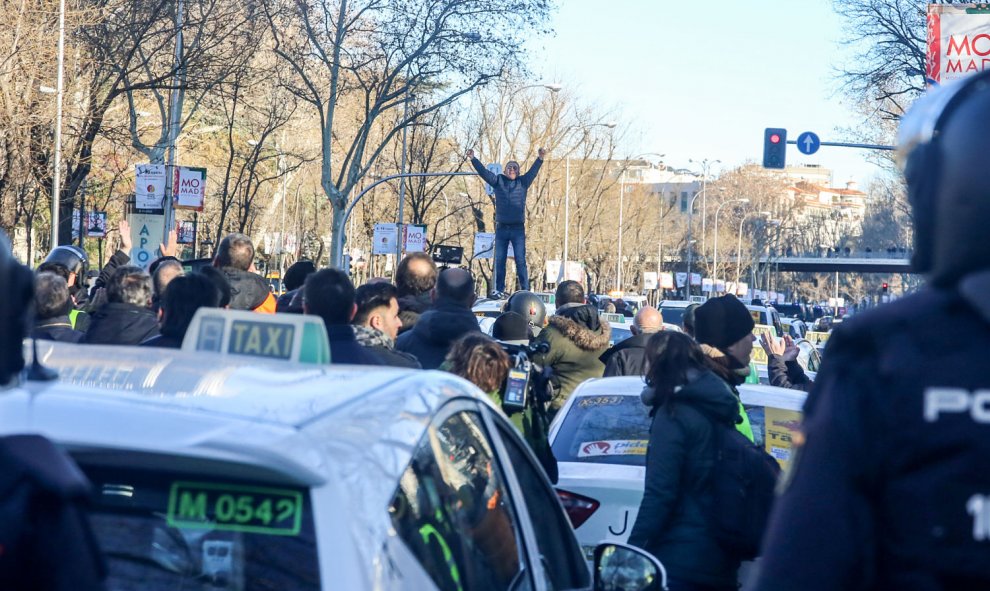 Un taxista se sube a un coche para dar una charla durante una concentración de taxistas en el Paseo de la Castellana de Madrid, donde el colectivo acampó en su séptimo día de huelga. | Ricardo Rubio / Europa Press