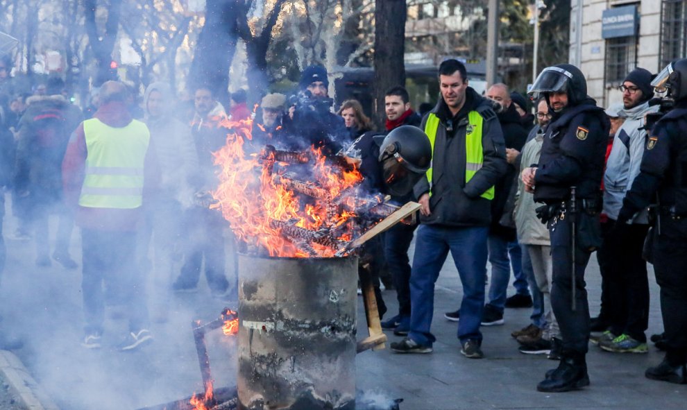 El miembro de la plataforma Caracol y portavoz del comité de huelga de taxis de Madrid, Saúl Crespo (a la derecha con chaleco amarillo) al lado de una hoguera que prendieron los taxistas de Madrid en el Paseo de la Castellana. | Ricardo Rubio / Europa Pr