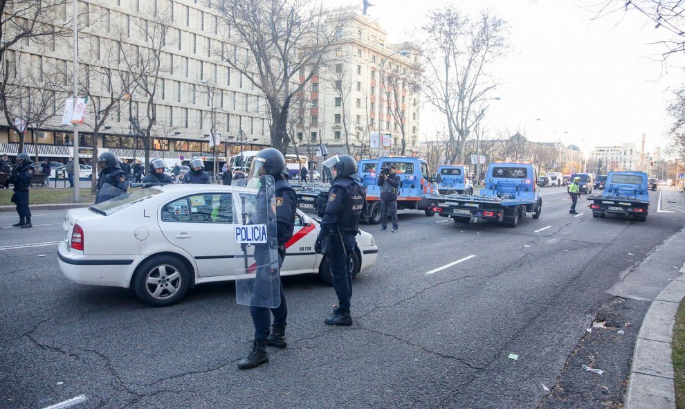 Agentes de la Policía Nacional junto a grúas municipales intentan retener la concentración de taxistas en el Paseo de la Castellana de Madrid. | Ricardo Rubio / Europa Press