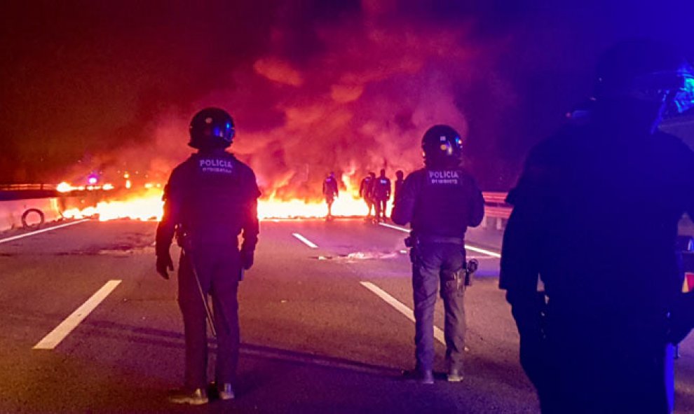 Mossos d'Esquadra observan una barricada en la AP-7. (PILAR SUÁREZ | REUTERS)