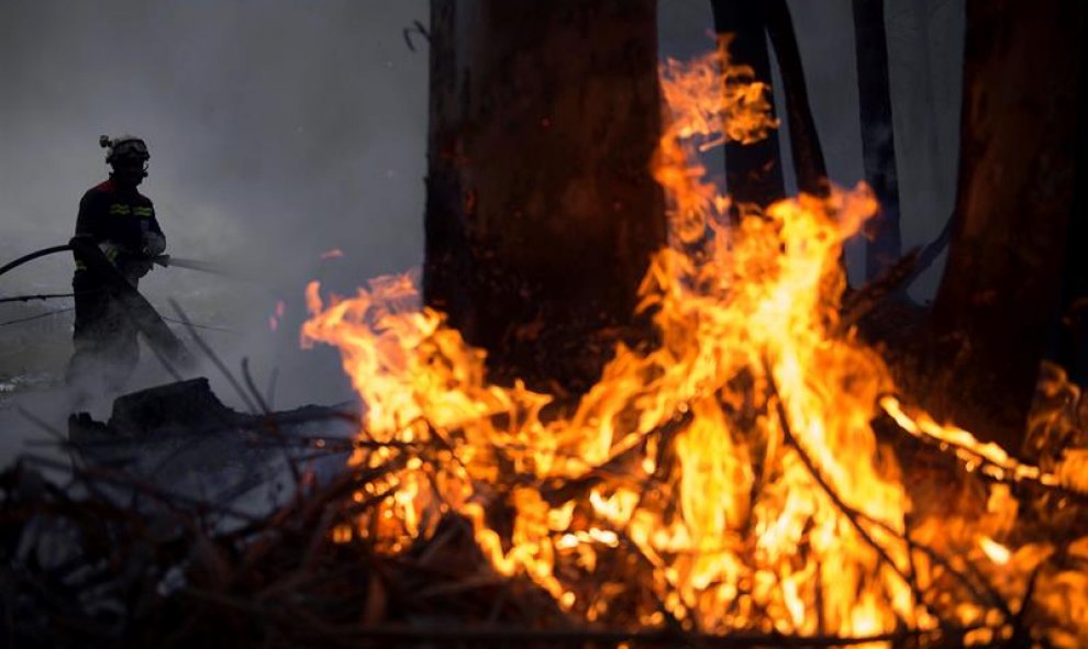 Un efectivo del Cuerpo de Bomberos del 112 de Cantabria durante las labores de extinción de un incendio forestal próximo a la localidad de Aes. El número de incendios activos en Cantabria ha bajado a 17 y los puntos más preocupantes están en Penagos, Aes