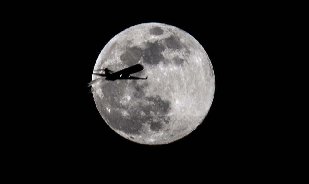 Un avión pasa frente a la luna llena durante el primer día de primavera en Fráncfort (Alemania). - EFE/ Armando Babani