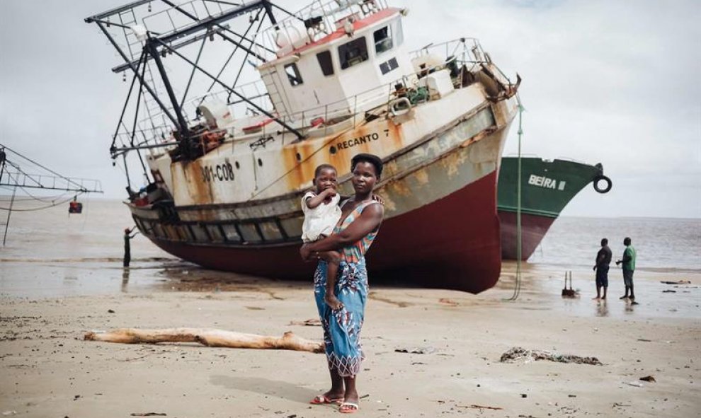 Amelia José Alberto, de 28 años, posa con Lurdes Mussa, de 5, en brazos, delante de un barco encallado en Beira. TIAGO PETINGA/EFE.