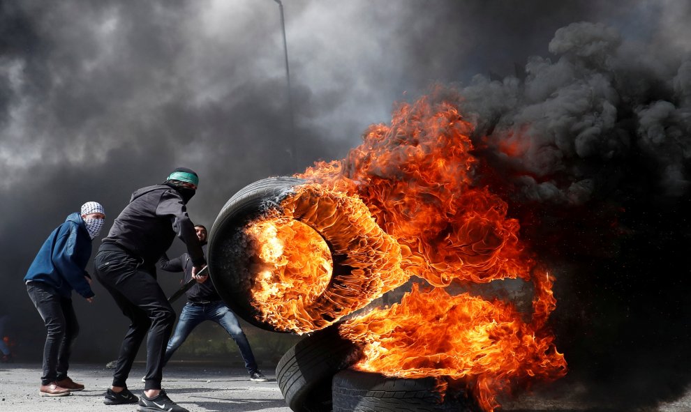 Un manifestante palestino mueve un neumático en llamas durante los enfrentamientos con las tropas israelíes. Reuters