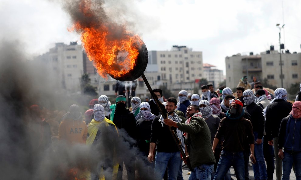 Manifestante palestino sostiene un neumático en llamas durante los enfrentamientos. Reuters