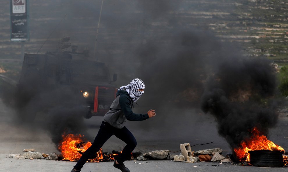 Manifestante palestino corre frente a un jeep militar israelí. Reuters