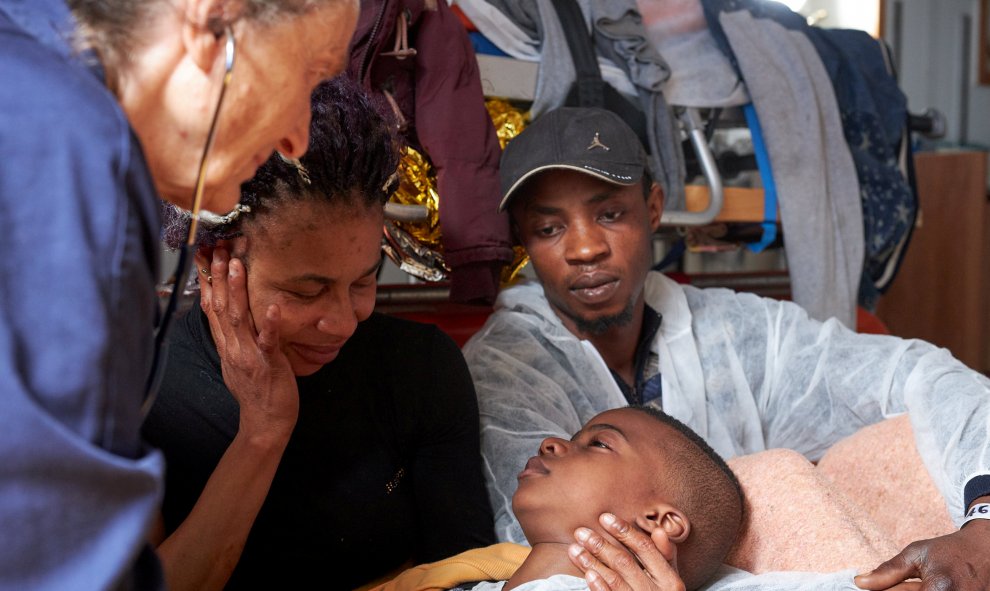 Un niño migrante yace en brazos de su madre en la sala de hospital del buque Alan Kurdi, dirigido por la organización benéfica alemana Sea-Eye, en el mar Mediterráneo. / REUTERS