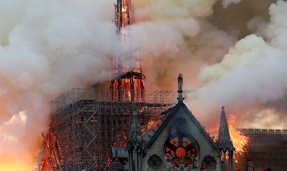 El humo ondea cerca de los andamios cuando el fuego envuelve la aguja de la catedral de Notre Dame. / Reuters