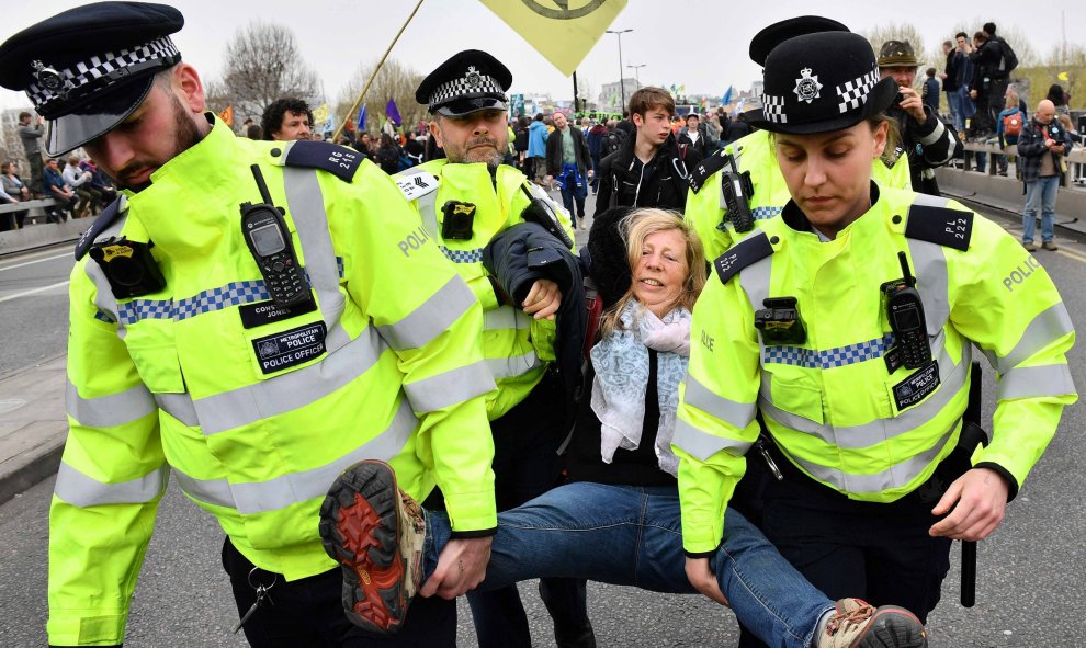16/04/2019 - Agentes de policía se llevan a una activista para desbloquear del puente de Waterloo en el segundo día de protestas en Londres | AFP/ Daniel Leal-Olivas