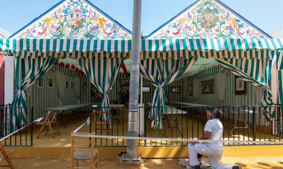 Un pintor última detalles para los preparativos de la Feria de Abril de Sevilla que comenzará mañana sábado con una ocupación hotelera del 87,9%, dos puntos porcentuales más que en la feria de 2018, según datos de la Asociación de Hoteles de Sevilla y Pro