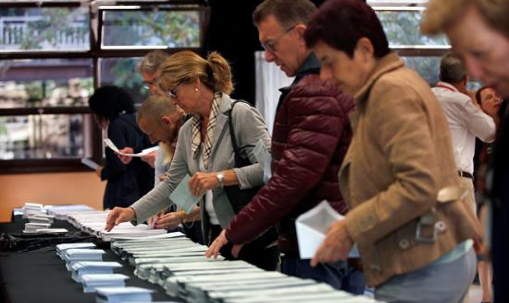 Varios ciudadanos escogen sus papeletas electorales en el Centre Cívic La Sedeta de Barcelona, uno de los 23.194 colegios electorales repartidos en toda España para las elecciones europeas, municipales y autonómicas, unos comicios en los que pueden votar.