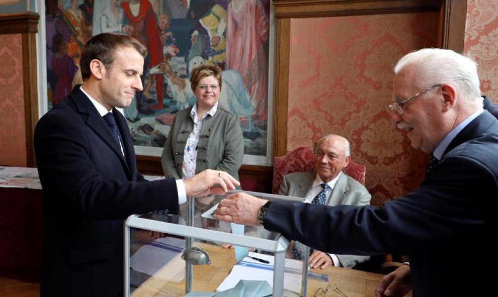 El presidente francés Emmanuel Macron (L) emite su voto en una mesa electoral en Le Touquet. EFE