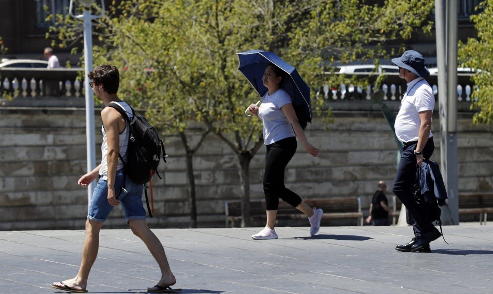 Una mujer se protege con un paraguas del calor en Bilbao, donde los valores registrados este viernes se sitúan entre 10 y 15 grados por encima de lo normal en el noroeste peninsular. | EFE