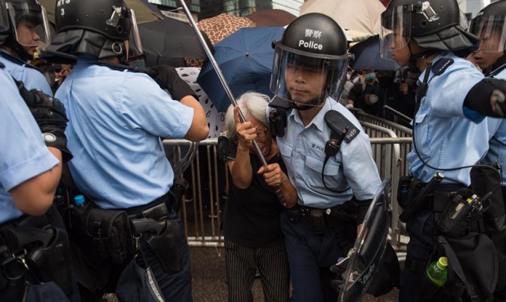 Un policía aleja a una manifestante durante un mitin contra las enmiendas a un proyecto de ley de extradición cerca del Consejo Legislativo en Hong Kong, China, el 12 de junio de 2019. EFE / Jerome Favre