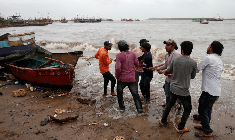 Los pescadores mueven un barco de pesca a un lugar más seguro a lo largo de la costa antes de la llegada a tierra del Ciclón Vayu en Veraval.
