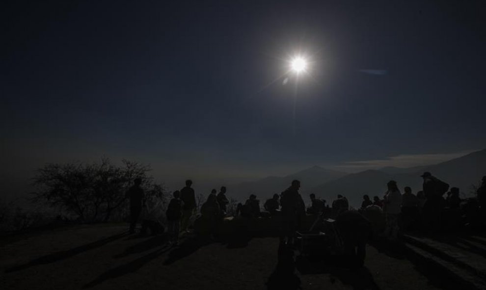 Cientos de personas acuden este martes a lo alto del Cerro San Cristóbal para observar el eclipse solar, en Santiago (Chile). EFE