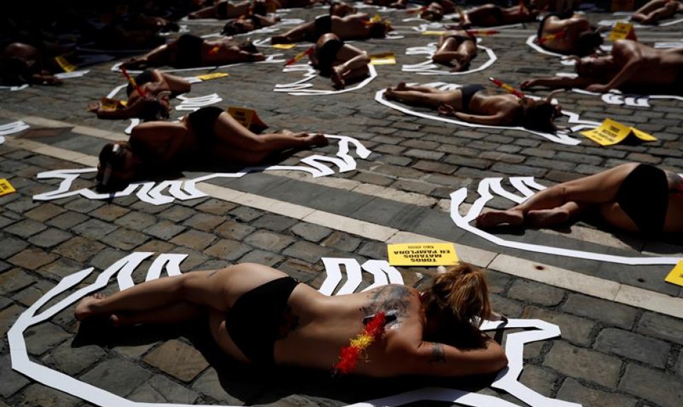 Semidesnudos, con cuernos, y banderillas en la espalda, los activistas se han tumbado sobre siluetas blancas de toros. EFE