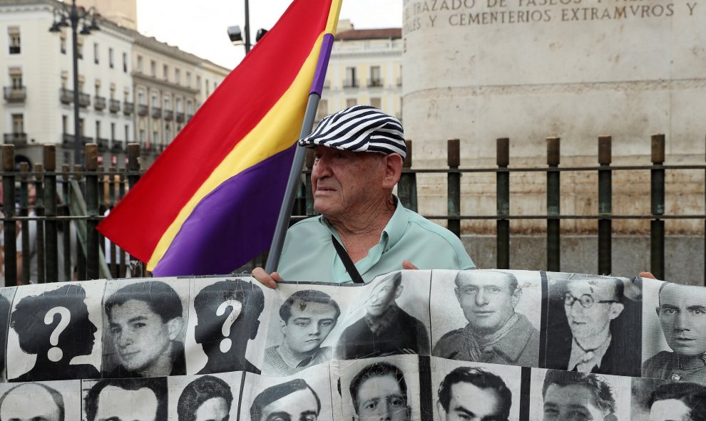 Manifestante sosteniendo un cartel con múltiples rostros de personas perdidas durante la dictadura.  - EFE/Kiko Huesca