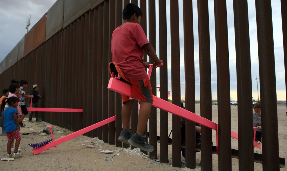 Familias americanas y mexicanas juegan con un balancín en mitad de la valla fronteriza que divide a los dos países LUIS TORRES (AFP).