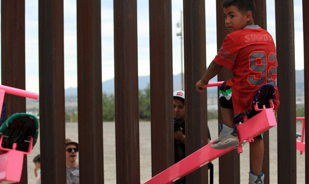 Un joven mexicano, en lo más alto del balancín, mientras un adulto empuja desde la parte norteamericana de la frontera. LUIS TORRES (AFP).