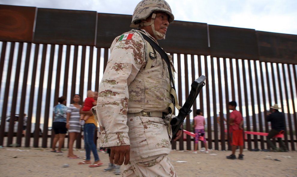 Varios militares del ejército mexicano patrullan la frontera mientras los niños se divierten con el balancín. LUIS TORRES (AFP)