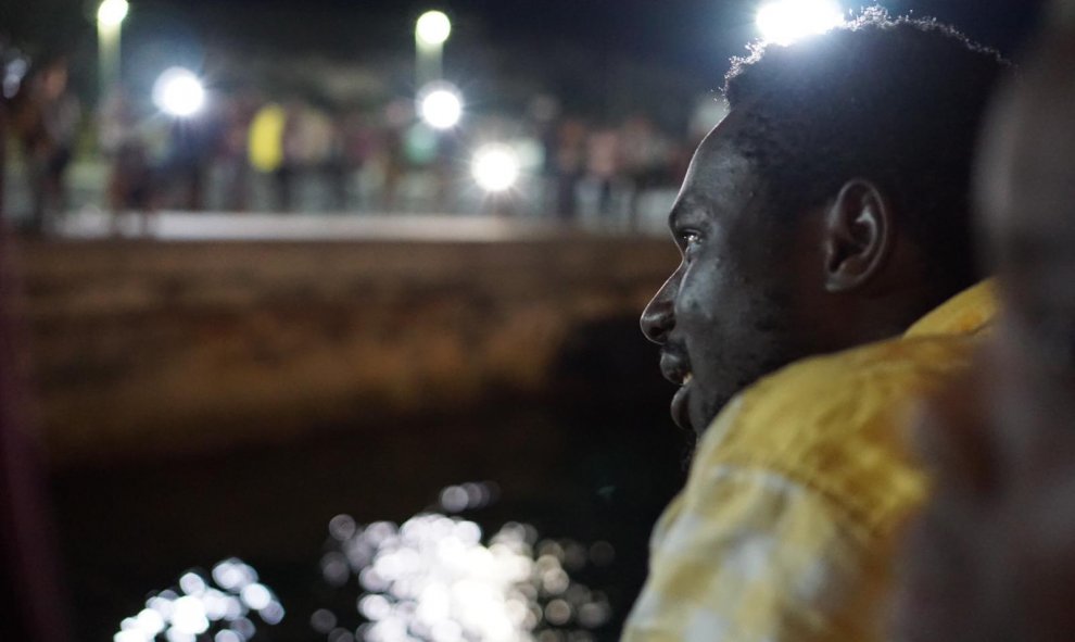 Uno de los migrantes mirando la costa cuando se acercaba el barco del Open Arms al puerto de Lampedusa. / EFE/Francisco Gentico