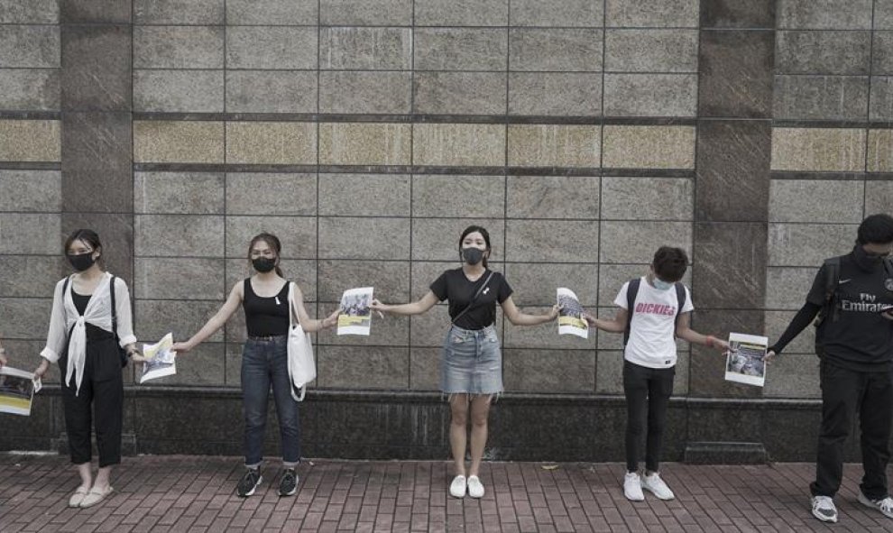 Estudiantes de la Universidad de la Ciudad de Hong Kong y de la Universidad Bapista forman una cadena humana en Hong Kong,mientras sujetan carteles. EFE / EPA / MIGUEL CANDELA