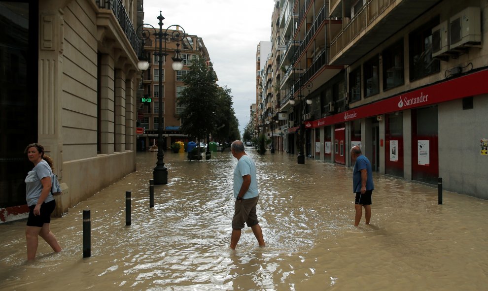 La gente camina por una calle inundada por las lluvias torrenciales en Orihuela, Alicante.- REUTERS/ JON NAZCA