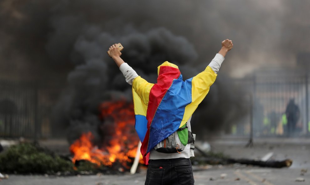 Un manifestante cubierto con una bandera ecuatoriana se para frente a una barricada durante una protesta contra las medidas de austeridad del presidente de Ecuador, Lenin Moreno, en Quito, Ecuador, 8 de octubre de 2019. REUTERS / Ivan Alvarado