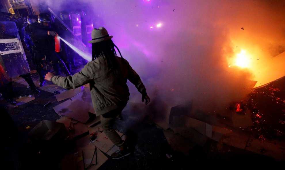 Un hombre se enfrenta un mosso que intenta apagar una fogata durante las protestas en el centro de Barcelona. /REUTERS
