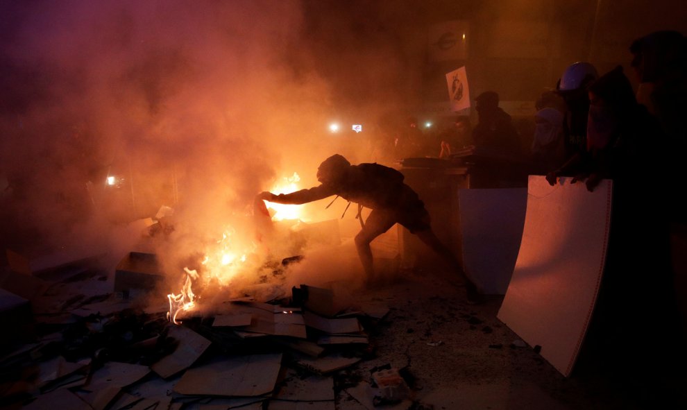 Un hombre encapuchado aviva el fuego durante las protestas en el centro de Barcelona. /REUTERS