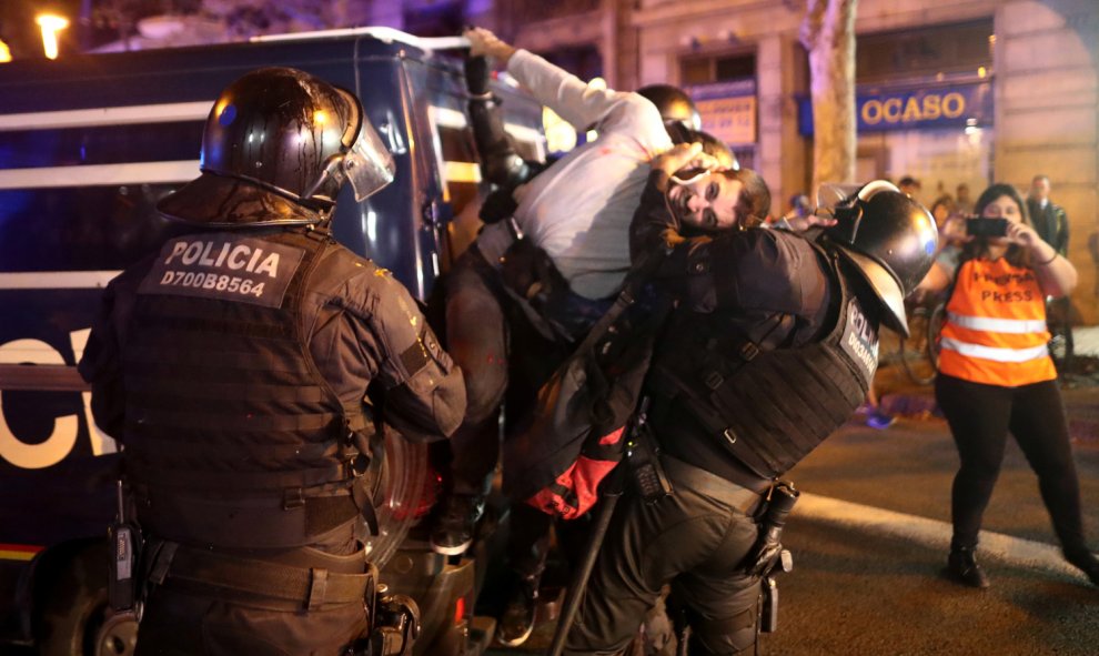 Dos mossos intentan soltar a un hombre agarrado a una furgoneta de la Policía durante las protestas que se han producido en el centro de Barcelona. /REUTERS