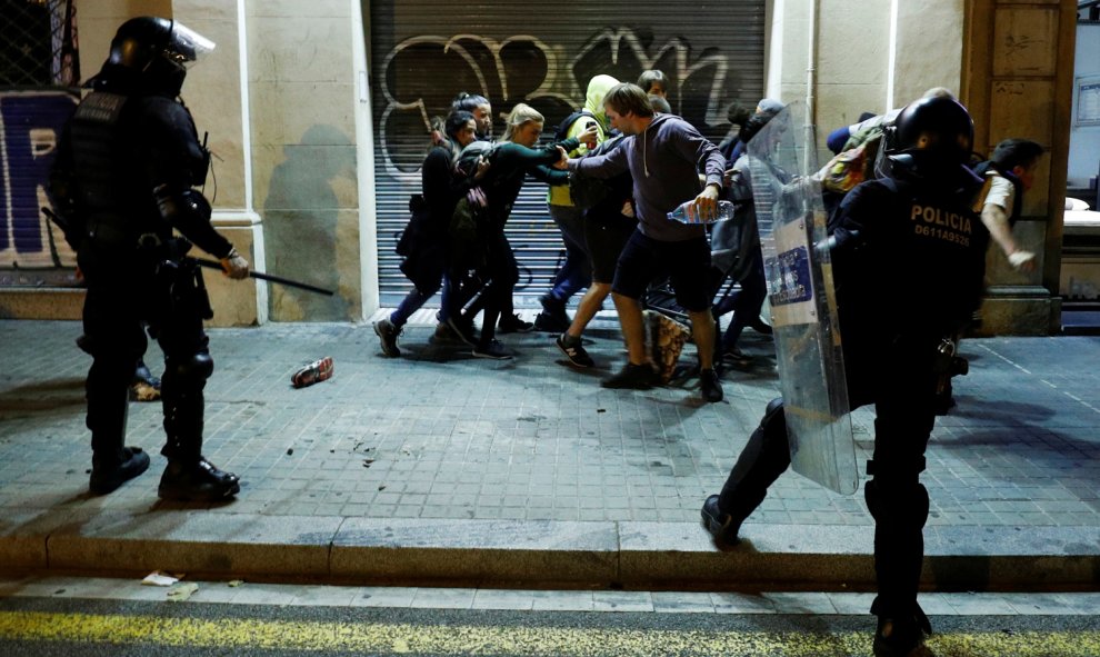 Varios jóvenes corren ante los Mossos durante los disturbios producidos en Barcelona. /REUTERS