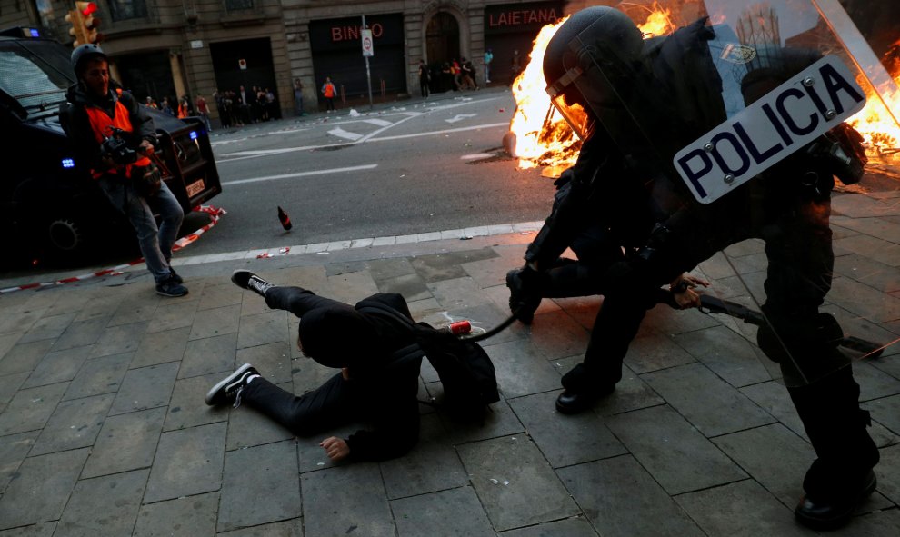 Un agente de la Policía Nacional golpe a un manifestante. / Reuters