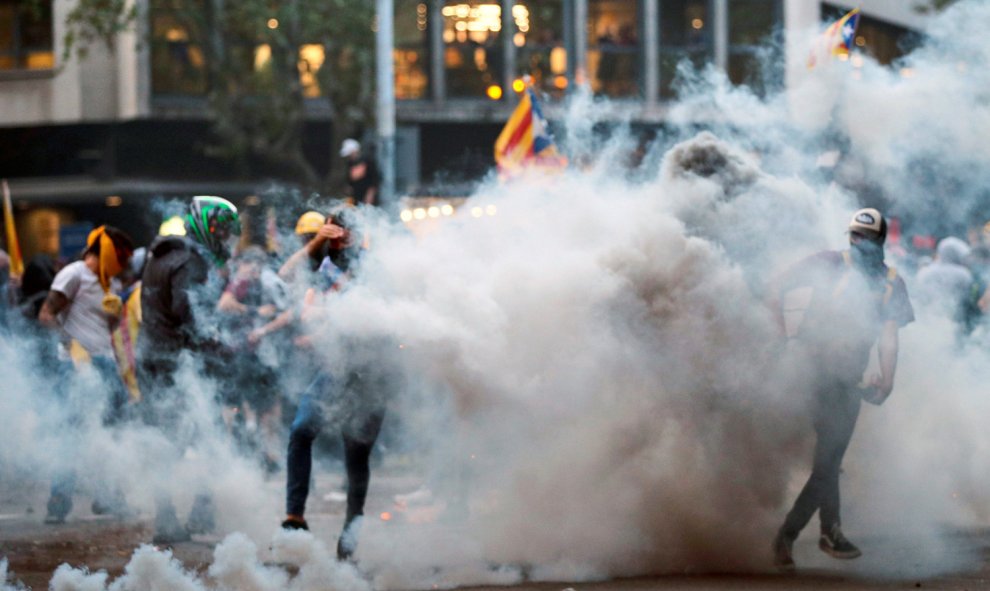 Manifestantes bajo una gran cortina de humo durante los incidentes que se están produciendo en Barcelona. /EFE